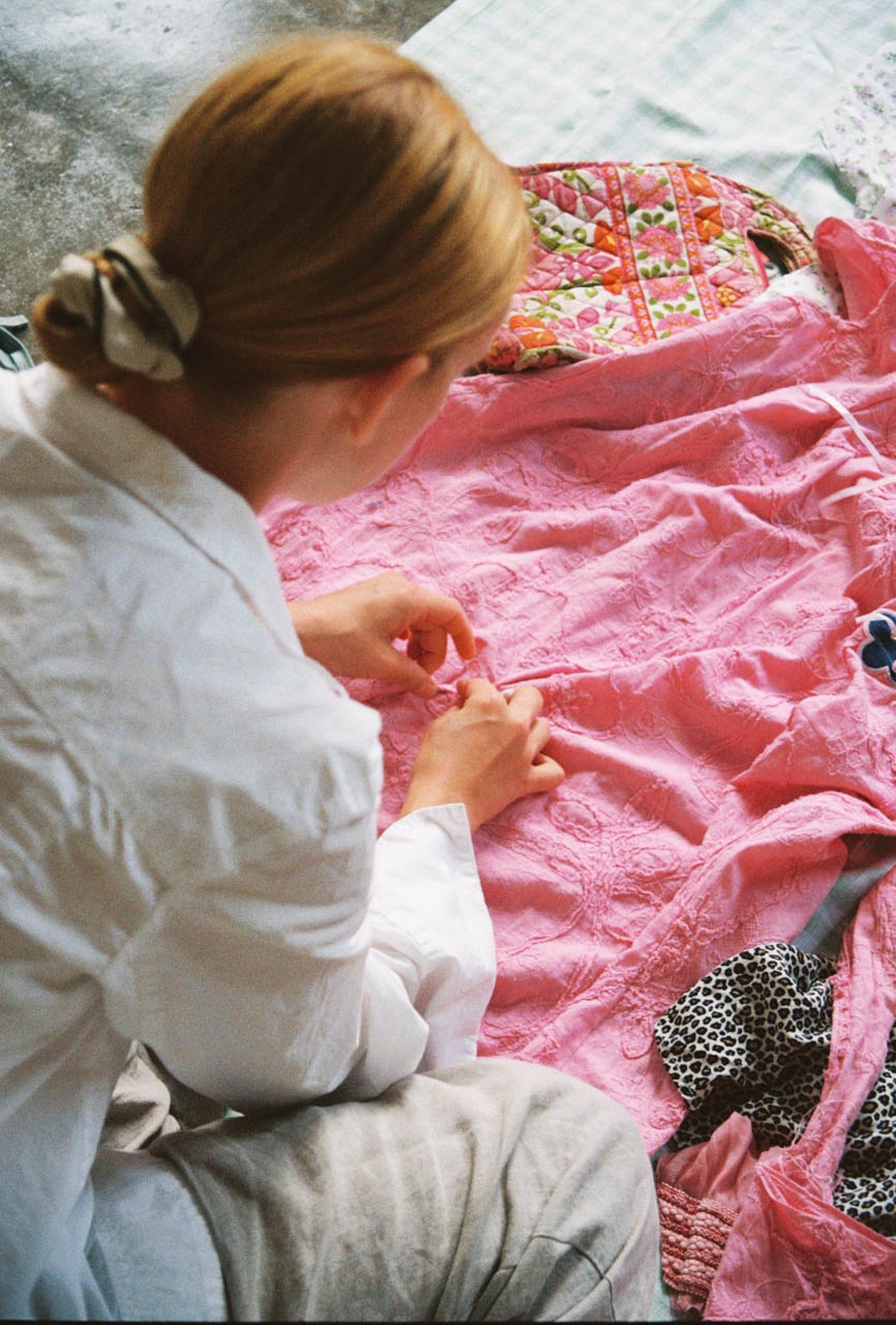 Hannah Maria Schmutterer hand sewing a pink textile work in her studio