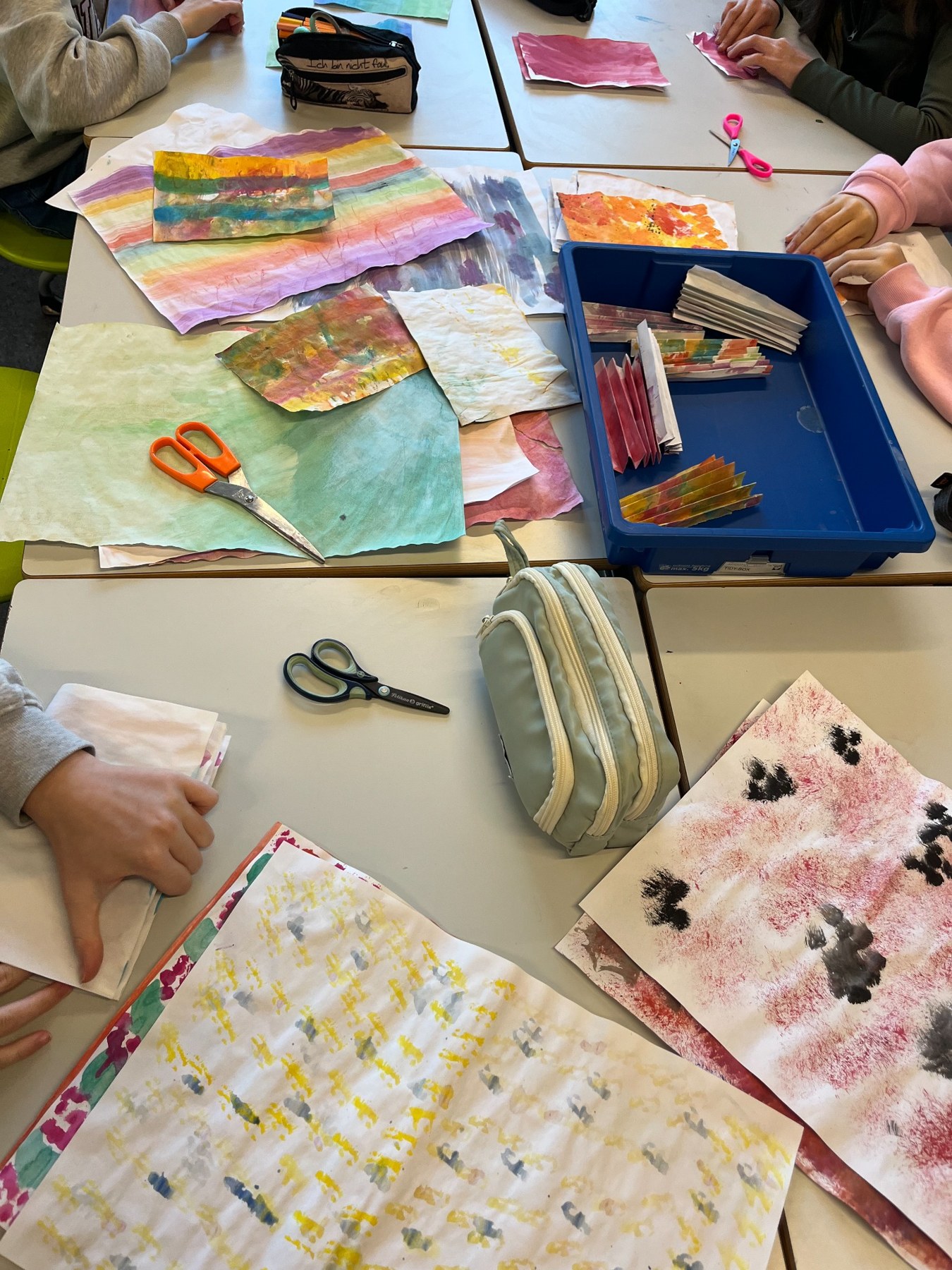 Students experimenting with paint and textile materials around a classroom table